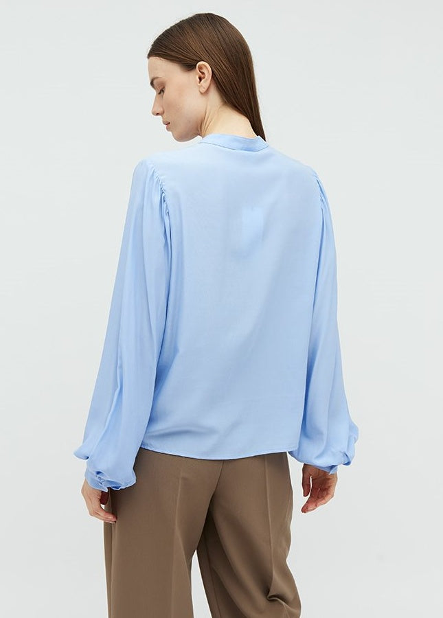 Mooie lichtblauwe blouse Keli van het merk mbyM. De blouse met mandarijnkraag en plooitjes aan de voorkant heeft lange mouwen met manchetten. De blouse heeft een ronde hals, een halve knoopsluiting aan de voorkant en een relaxte pasvorm. Shop de nieuwe collectie dames blouses, lichtblauwe blouses, mbyM blouses online.