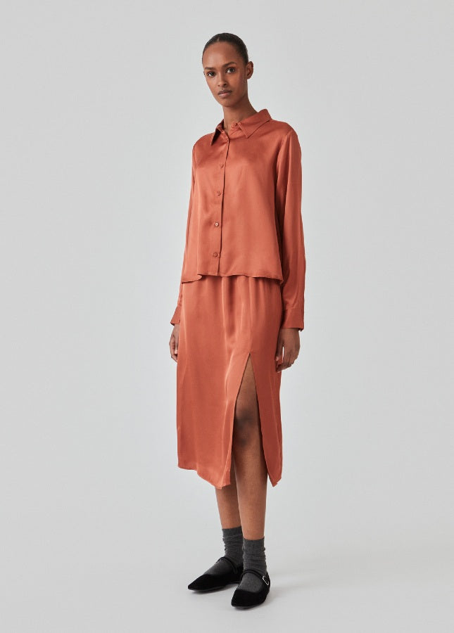 Maple satijnlook rok Flore van het merk Modstrom. De satijnen midi-rok heeft een split aan de voorkant. De Flore rok is halflang en hoog getailleerd met elastische taille. Shop de nieuwe collectie Modstrom kleding. Midi-rokken, Satijnlook rokken, roestbruine rokken, Modstrom rokken shop je online bij Boetiek Aniek.