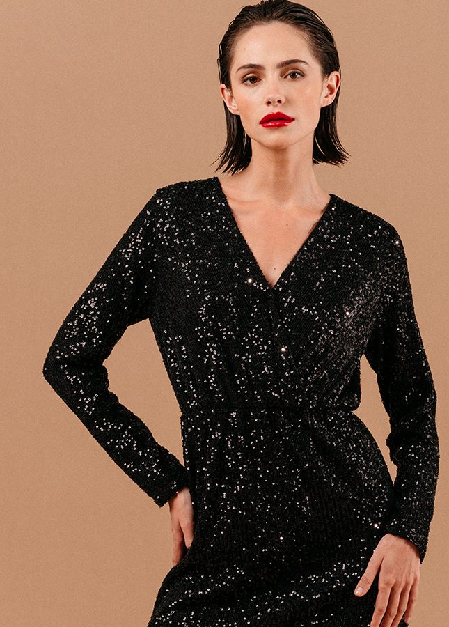 Zwarte paillettenjurk Love van het merk Grace & Mila. De zwarte korte pailletenjurk heeft een V-hals (met drukknoopje), lange mouwen en een elastische tailleband. De paillettenjurk heeft een zwarte onderjurk. De perfecte zwarte jurk voor een feestje of voor tijdens de feestdagen. Shop paillettenjurken online.