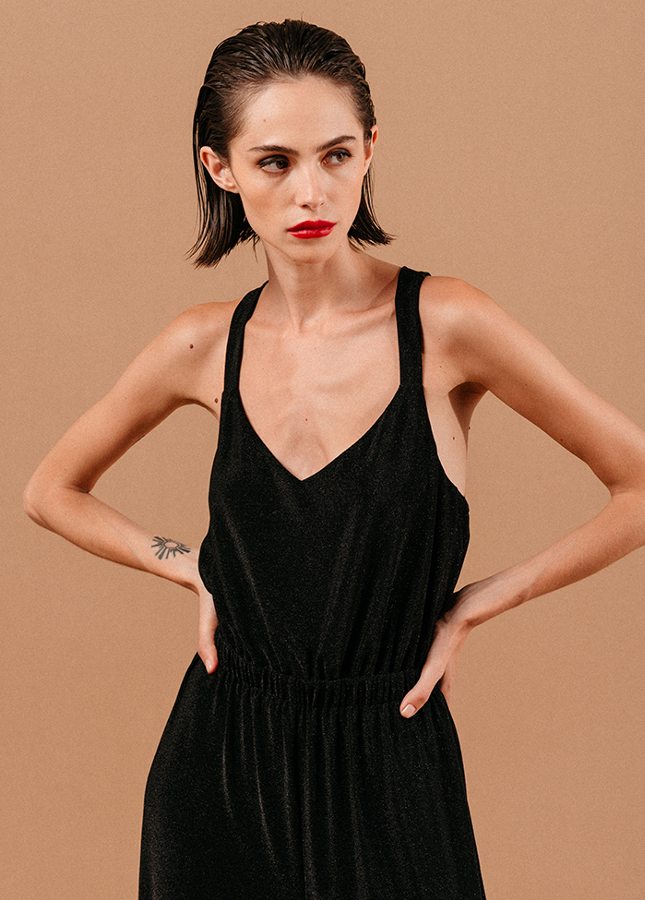 Mooie zwarte jumpsuit Loyale van het merk Grace & Mila. De zwarte jumpsuit met lichte glitter een brede bandjes die gekruist lopen op de rug, een V-Hals, elastische tailleband en lang wijde pijpen. De perfecte jumpsuit voor een feestje of voor tijdens de feestdagen. Shop zwarte jumpsuits online bij Boetiek Aniek.
