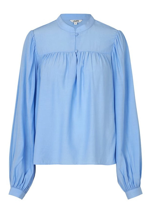 Mooie lichtblauwe blouse Keli van het merk mbyM. De blouse met mandarijnkraag en plooitjes aan de voorkant heeft lange mouwen met manchetten. De blouse heeft een ronde hals, een halve knoopsluiting aan de voorkant en een relaxte pasvorm. Shop de nieuwe collectie dames blouses, lichtblauwe blouses, mbyM blouses online.