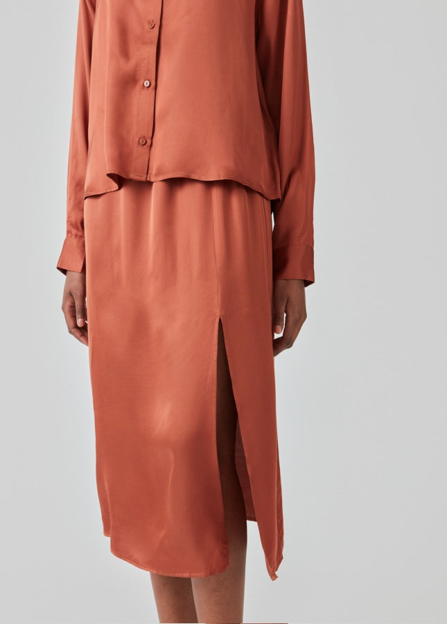 Maple satijnlook rok Flore van het merk Modstrom. De satijnen midi-rok heeft een split aan de voorkant. De Flore rok is halflang en hoog getailleerd met elastische taille. Shop de nieuwe collectie Modstrom kleding. Midi-rokken, Satijnlook rokken, roestbruine rokken, Modstrom rokken shop je online bij Boetiek Aniek.