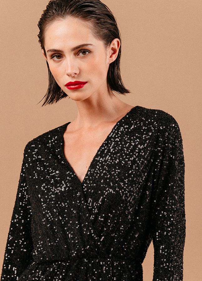 Zwarte paillettenjurk Love van het merk Grace & Mila. De zwarte korte pailletenjurk heeft een V-hals (met drukknoopje), lange mouwen en een elastische tailleband. De paillettenjurk heeft een zwarte onderjurk. De perfecte zwarte jurk voor een feestje of voor tijdens de feestdagen. Shop paillettenjurken online.
