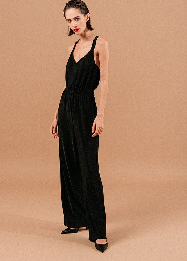 Mooie zwarte jumpsuit Loyale van het merk Grace & Mila. De zwarte jumpsuit met lichte glitter een brede bandjes die gekruist lopen op de rug, een V-Hals, elastische tailleband en lang wijde pijpen. De perfecte jumpsuit voor een feestje of voor tijdens de feestdagen. Shop zwarte jumpsuits online bij Boetiek Aniek.