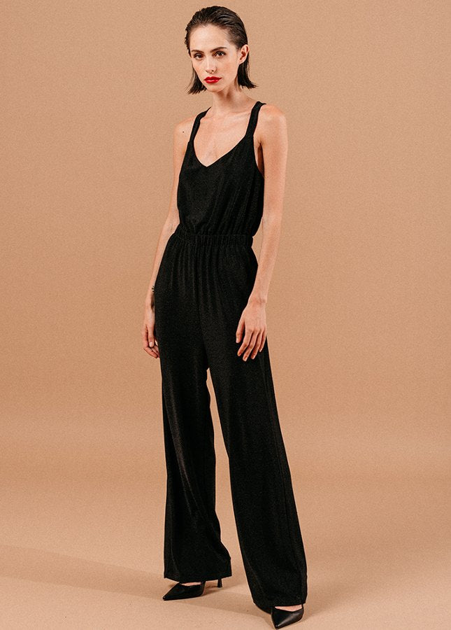 Mooie zwarte jumpsuit Loyale van het merk Grace & Mila. De zwarte jumpsuit met lichte glitter een brede bandjes die gekruist lopen op de rug, een V-Hals, elastische tailleband en lang wijde pijpen. De perfecte jumpsuit voor een feestje of voor tijdens de feestdagen. Shop zwarte jumpsuits online bij Boetiek Aniek.